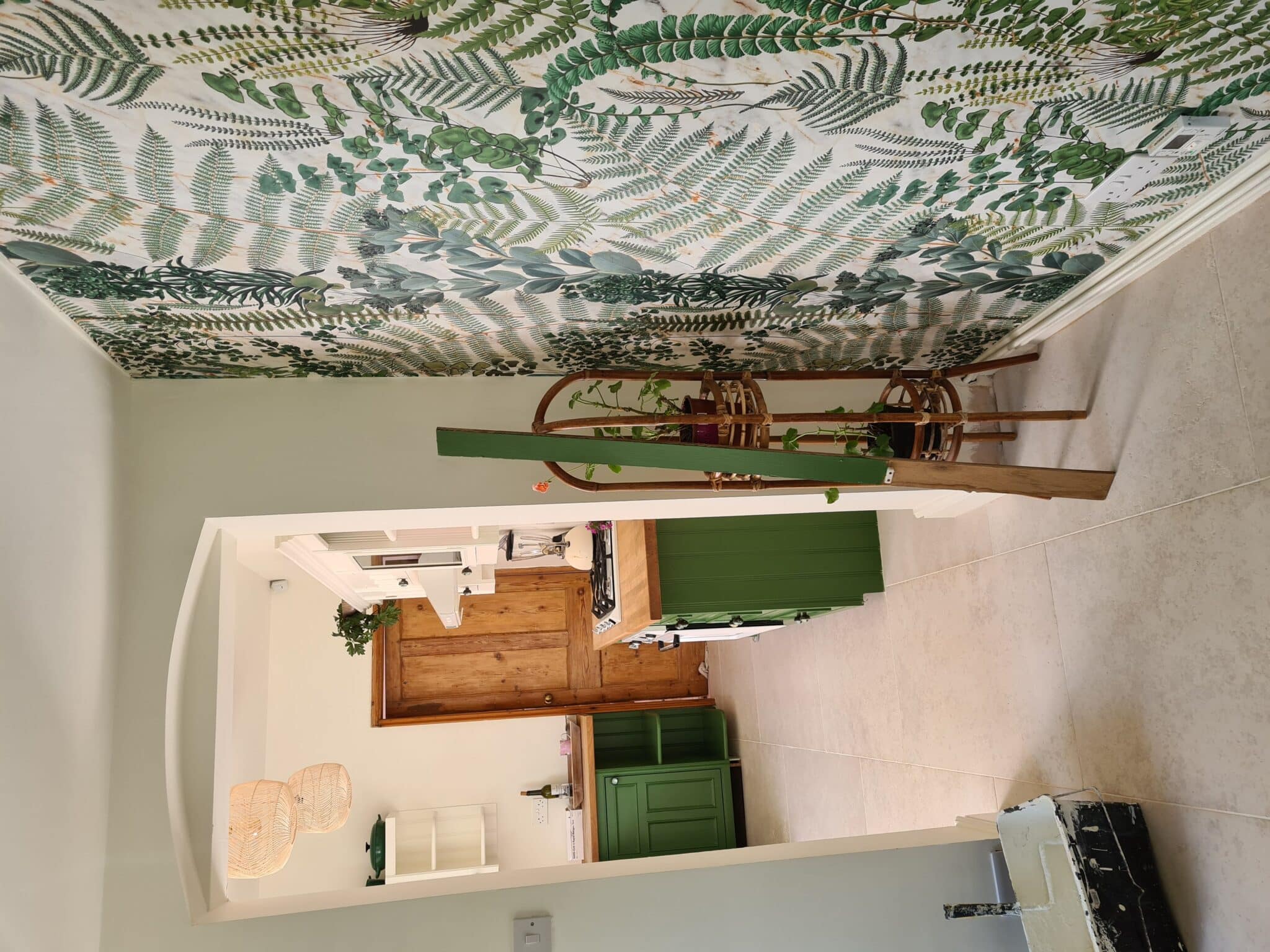 Botanical leaf wallpaper in a modern Leicester kitchen with green cabinetry and natural wood finishes.