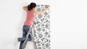 woman wallpapering a house wall