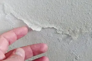 The paint on the wall of a house is peeling and blistering.