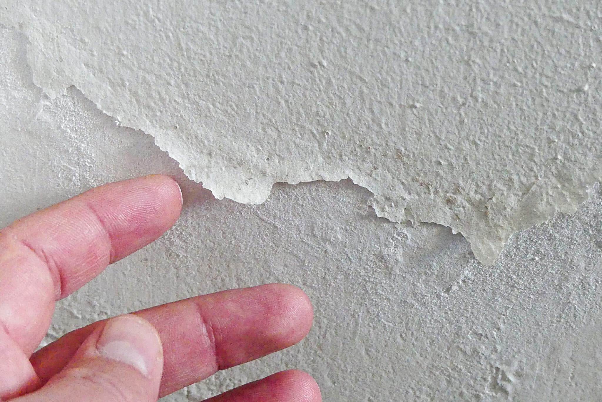 The paint on the wall of a house is peeling and blistering.