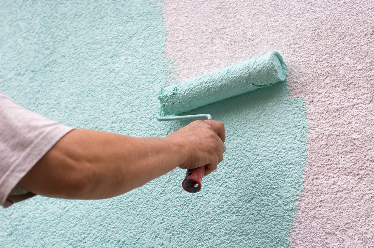 painting wall with a roll in green outdoor