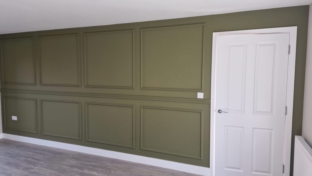 Beautiful olive green painted wall panelling contrasting with a crisp white interior door and skirting boards, completed by professional painters in Leicester.