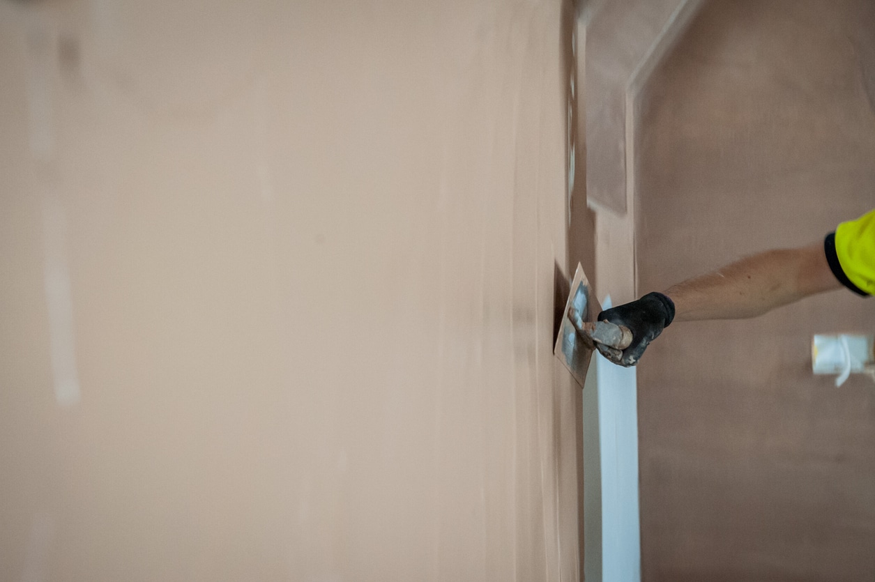 Photo shows the arm of a plasterer smoothing a final coat of plaster using a Plasterer's Float